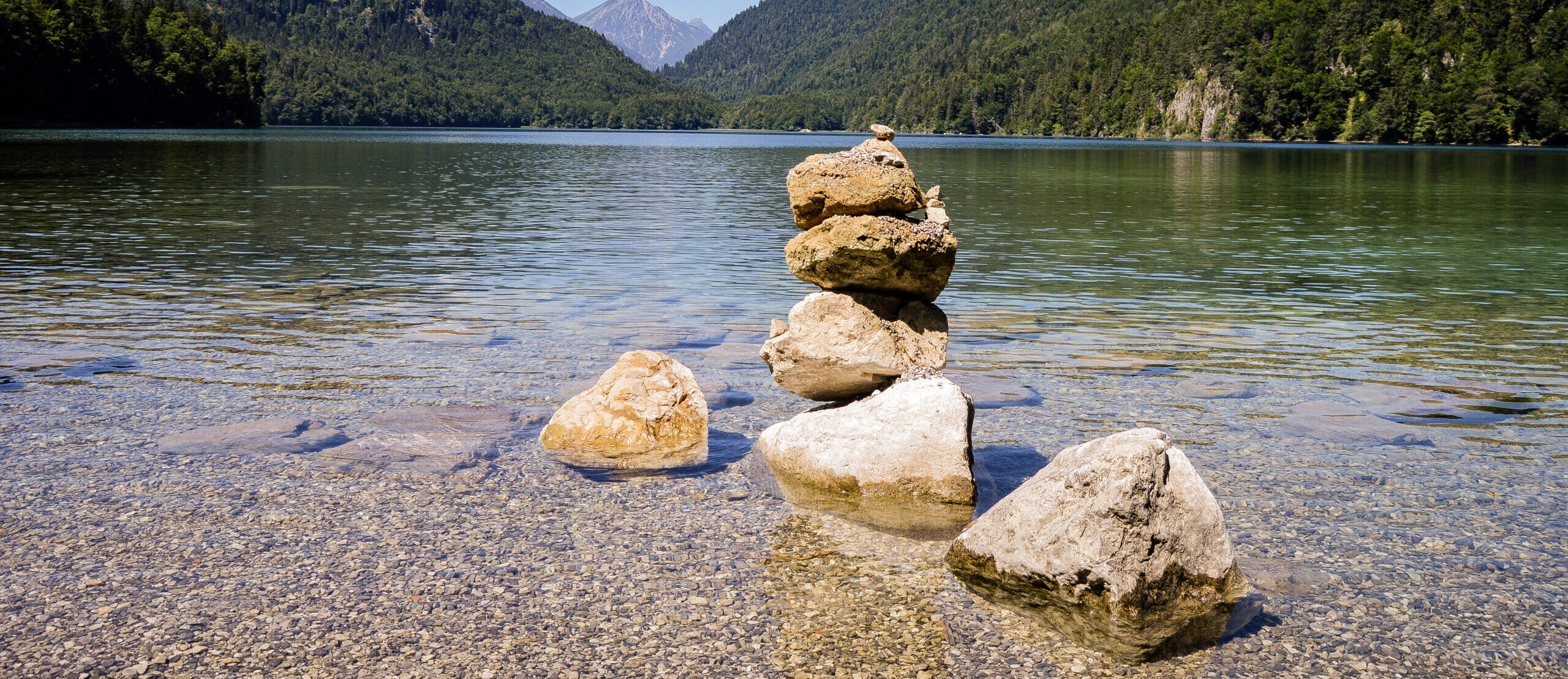 A beautiful view of a lake with turquoise water and stone cairn