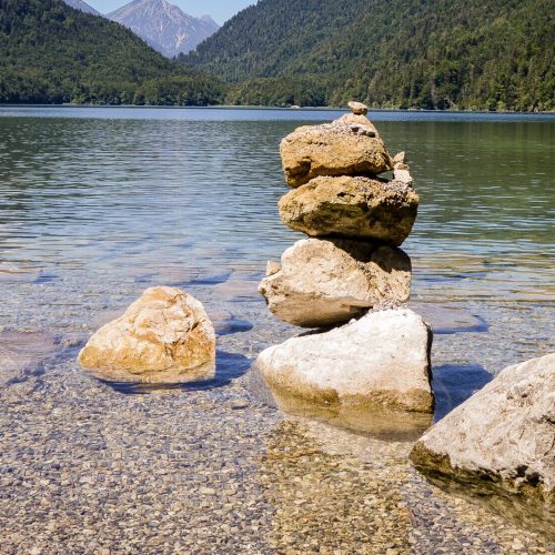 A beautiful view of a lake with turquoise water and stone cairn